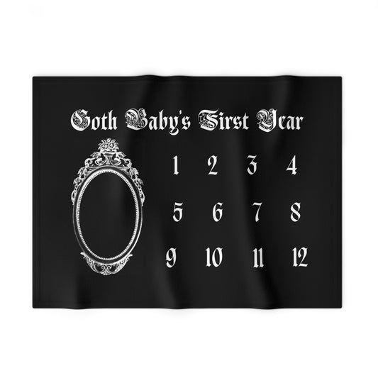 Black blanket with white baby milestone numbers and decorative elements on a white background